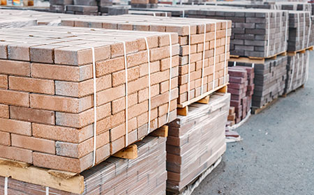 pallets and packages of freshly produced red bricks in a construction warehouse on the street. Concept of repair and building materials