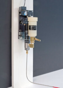 Close-up of a precision spray nozzle assembly mounted on a wall, showcasing its components and fluid delivery system.