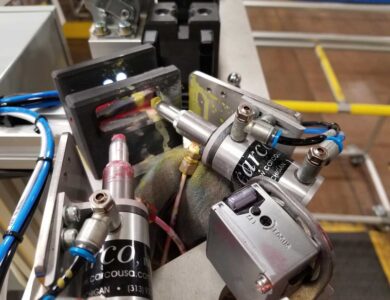 Close-up of precision machinery components with various tubes, wires, and fittings in an industrial setting.